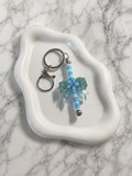 Porte-clés papillon bleu pailleté avec perles turquoise et rayées