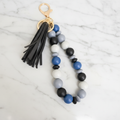 Porte-clés bracelet perles silicone bleu pompon noir - fond marbré vue 1