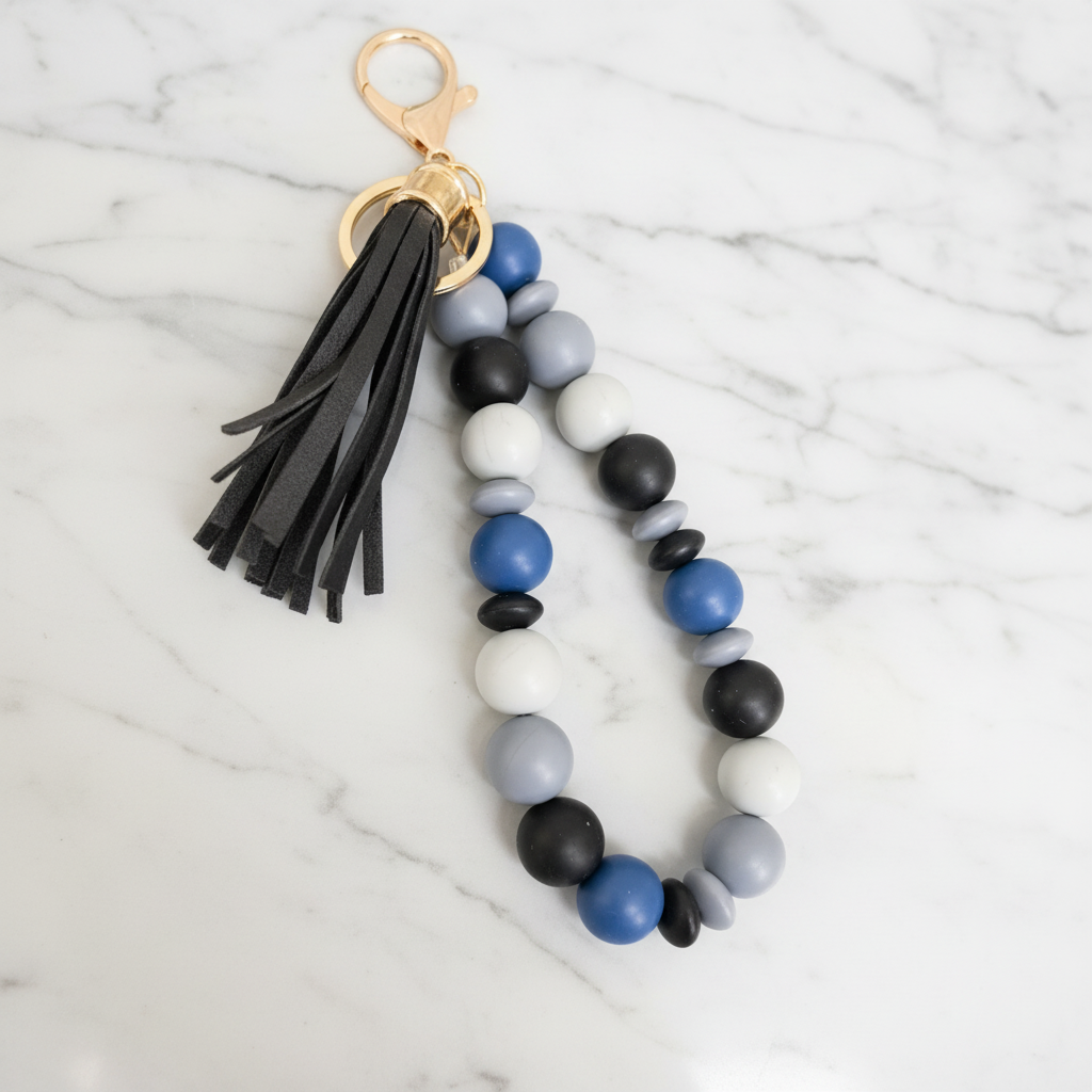 Porte-clés bracelet perles silicone bleu pompon noir - fond marbré vue 1