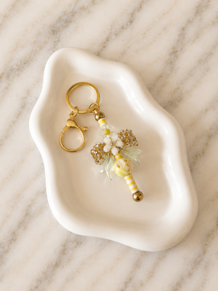 Porte-clés nœud doré avec fleurs blanches et clochette